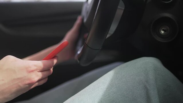 Using a mobile phone in a traffic jam while driving a car. A person writes a message in the messenger sitting behind the wheel, close-up 4K 10 BIT