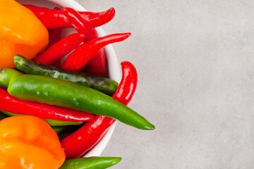 bright small red and green chilies on light grey with copy space