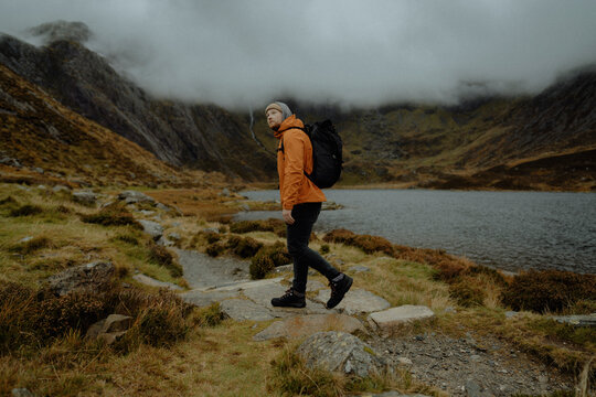 Man hiking on wet rocks at mountain lake, Llyn Padarn, Snowdonia, Wales
