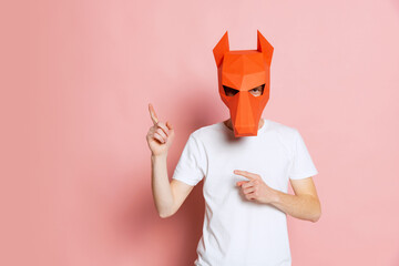 Creative portrait of young man in white t-shirt with cardboard animal mask on his head isolated on...
