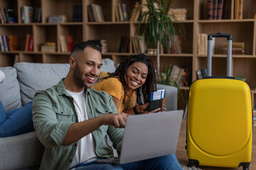 Happy young black couple using laptop and searching place for travel, getting ready for honeymoon holiday trip concept