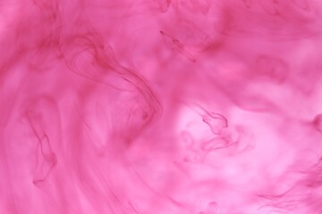 Fototapeta na wymiar Shallow depth of field shot of swirling pink and blue ink in water - soft flowing abstract and soothing backdrop