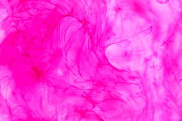 Fototapeta na wymiar Shallow depth of field shot of swirling pink and blue ink in water - soft flowing abstract and soothing backdrop