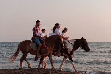The family spends time with their children while riding horses together on a sandy beach. Selective focus 