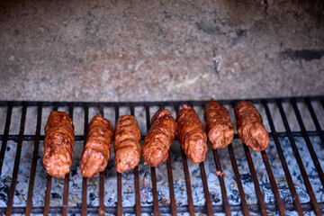 Preparing meat rolls called mici or mititei on barbecue. close up of grill with burning fire with flame and smoke.