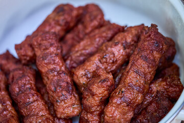 Preparing meat rolls called mici or mititei on barbecue. close up of grill with burning fire with flame and smoke.