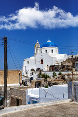 Fototapeta premium White church with a blue dome on Santorini island in Greece. Hot summer sun day.