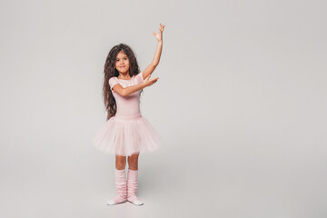 Little swarthy ballerina dancer in a pink tutu academy student posing on white background 