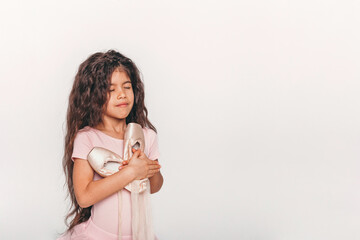 Little swarthy ballerina dancer in a pink tutu academy student posing on white background 