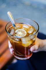 Hand holding a glass of coffee. Coffee with slice of lemon.