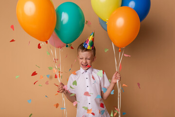 Cheerful little boy with balloons on the beige background