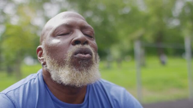 Close portrait of senior black male getting his breath back and recovering after a workout session