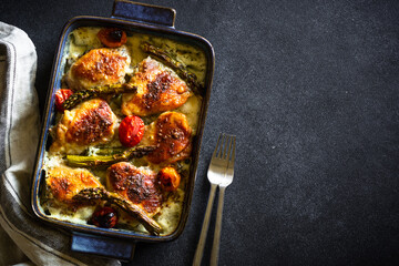 Baked chicken thighs with asparagus and vegetables in a creamy sauce.