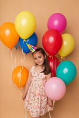 Obraz premium Happy Birthday party. Child girl with balloons on beige background