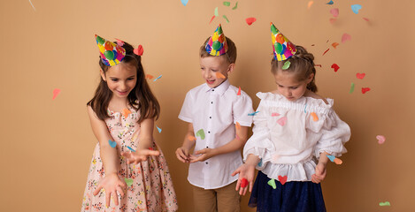 Happy birthday children girls and boy with confetti on beige background