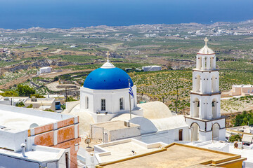 White church with a blue dome on Santorini island in Greece. Hot summer sun day.