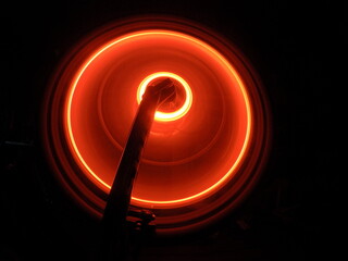 bright orange color neon circle on a moving wheel on a black background