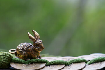 A metal rabbit figurine with Chinese coins. An esoteric symbol.