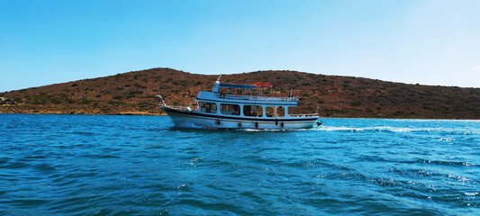 Pleasure boat in the bay against the background of a hilly island. Elounda, Crete, Greece
