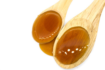 Date syrup and two wood spoons on white background - top view