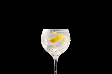 Gin tonic cocktail drink into a glass on black background