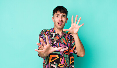 young adult hispanic man feeling terrified, backing off and screaming in horror and panic, reacting...