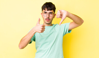 young adult hispanic man feeling confused, clueless and unsure, weighting the good and bad in...