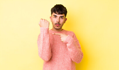 young adult hispanic man looking impatient and angry, pointing at watch, asking for punctuality,...