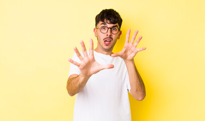 young adult hispanic man feeling terrified, backing off and screaming in horror and panic, reacting...