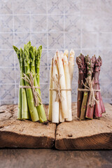 Green, white and purple asparagus on a kitchen background