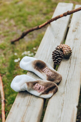 A little kid's dirty socks on a wooden bench in a field.