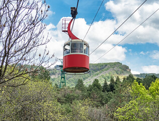 Red cable car rising people to mountain top at sunny summer day