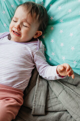 Fototapeta premium a child with a catheter in his hand cries a lot and cries while lying in bed in the hospital