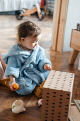 little girl playing in home clothes on the floor among books and toys, everyday routine child