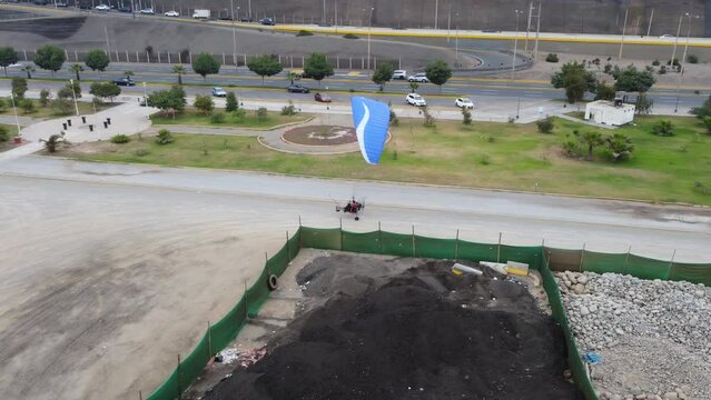 Drone video of a paraglider smoothly landing on a dirt track in Lima, Peru.