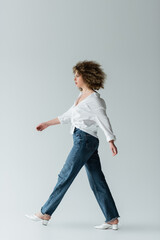 Side view of stylish woman walking on white background.