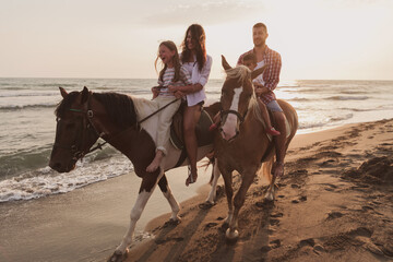 The family spends time with their children while riding horses together on a sandy beach. Selective...