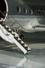 Stairs and door of private jet in hangar ready to fly- stock photo
