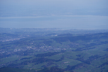 Aerial view with Mountains and midland and lake Bodensee in the background seen from Säntis peak at Alpstein Mountains on a sunny spring day. Photo taken April 19th, 2022, Säntis, Switzerland.