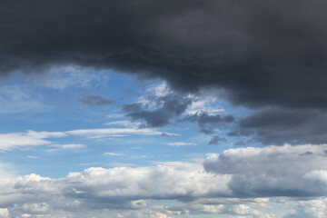Epic Dramatic storm dark grey cumulus rain clouds against blue sky background texture, thunderstorm. Darkness and light