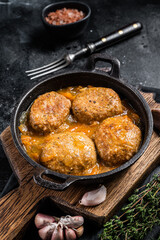 Fish balls with tuna in tomato sauce in a pan. Black background. Top view