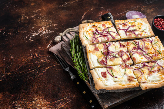 French tarte flambee with cream cheese, bacon and onions. Flammkuchen from Alsace region.  Dark background. Top view. Copy space