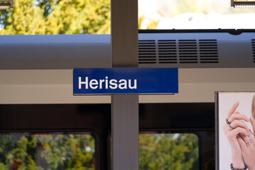 Railway station of City of Herisau, Canton Appenzell Ausserrhoden, with blue sign on a sunny spring day. Photo taken April 19th, 2022, St. Gallen, Switzerland.