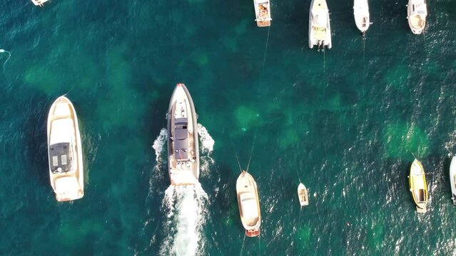 Moving speedboat between other boats, overhead aerial view.