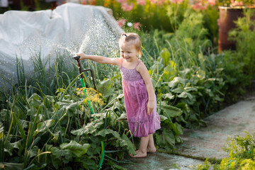 Funny child toddler in garden with sprinkler, freshness on summer day and happy childhood