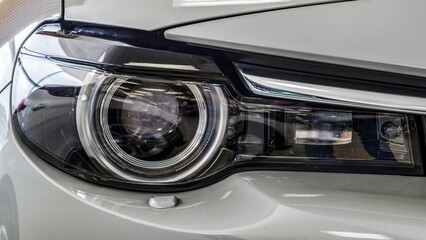 Front headlight of a modern car. Light gray color. Close-up