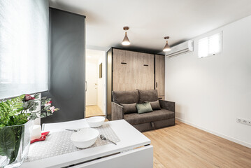 Kitchen with white furniture and stainless steel appliances, white stone countertop with small appliances on it in an apartment with sloping ceilings.
