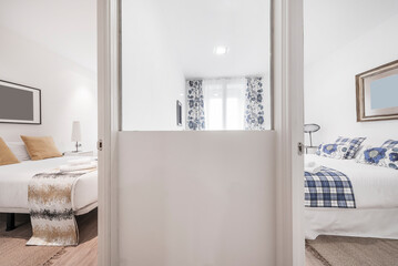 living room with a three-seater sofa bed upholstered in gray fabric, with various cushions in shades of blue and auxiliary black metal and glass coffee tables