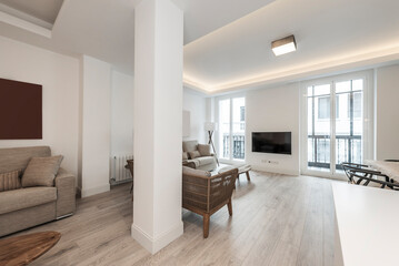 Fototapeta na wymiar Living room with fabric sofas, rattan armchairs, windows to the street and light wood flooring