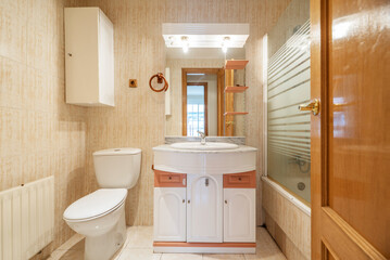 Bathroom with shower cabin with screens, shiny white wooden furniture, marble countertop and rectangular mirror with lights